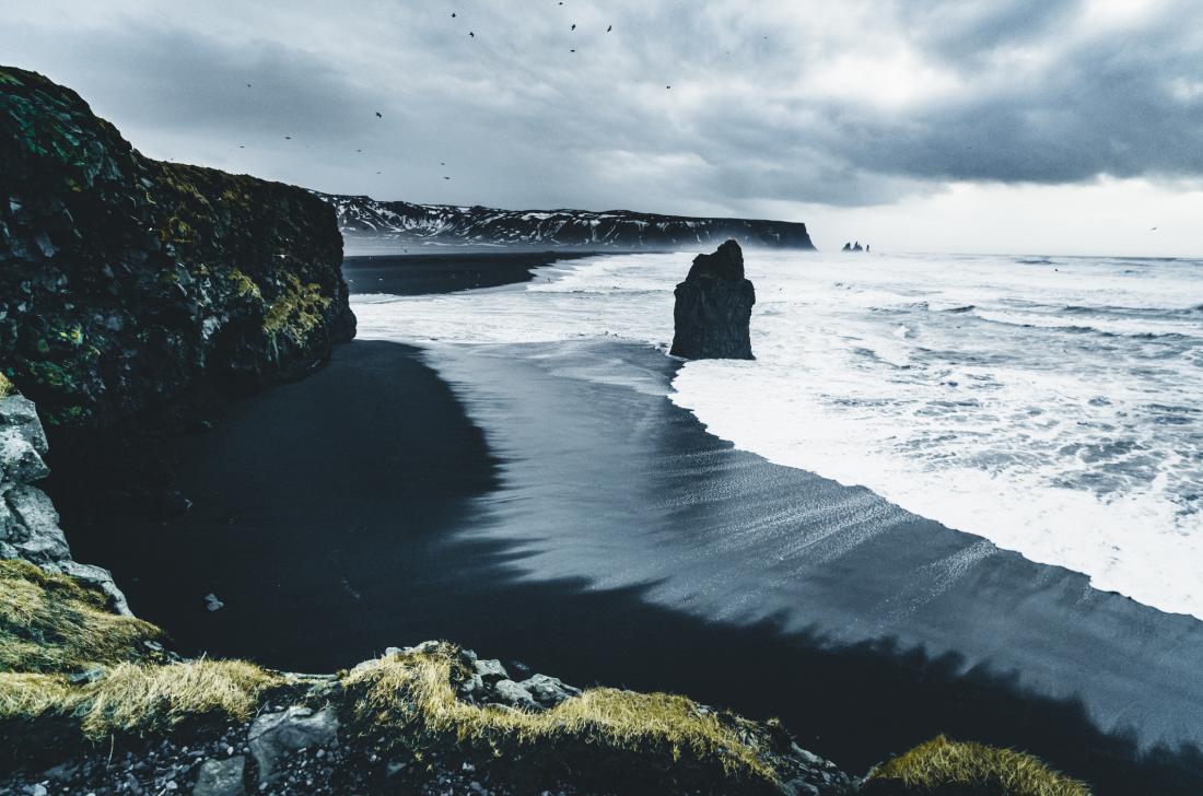 Sončni vzhod na znameniti črni peščeni plaži Reynisfjara na Islandiji. 